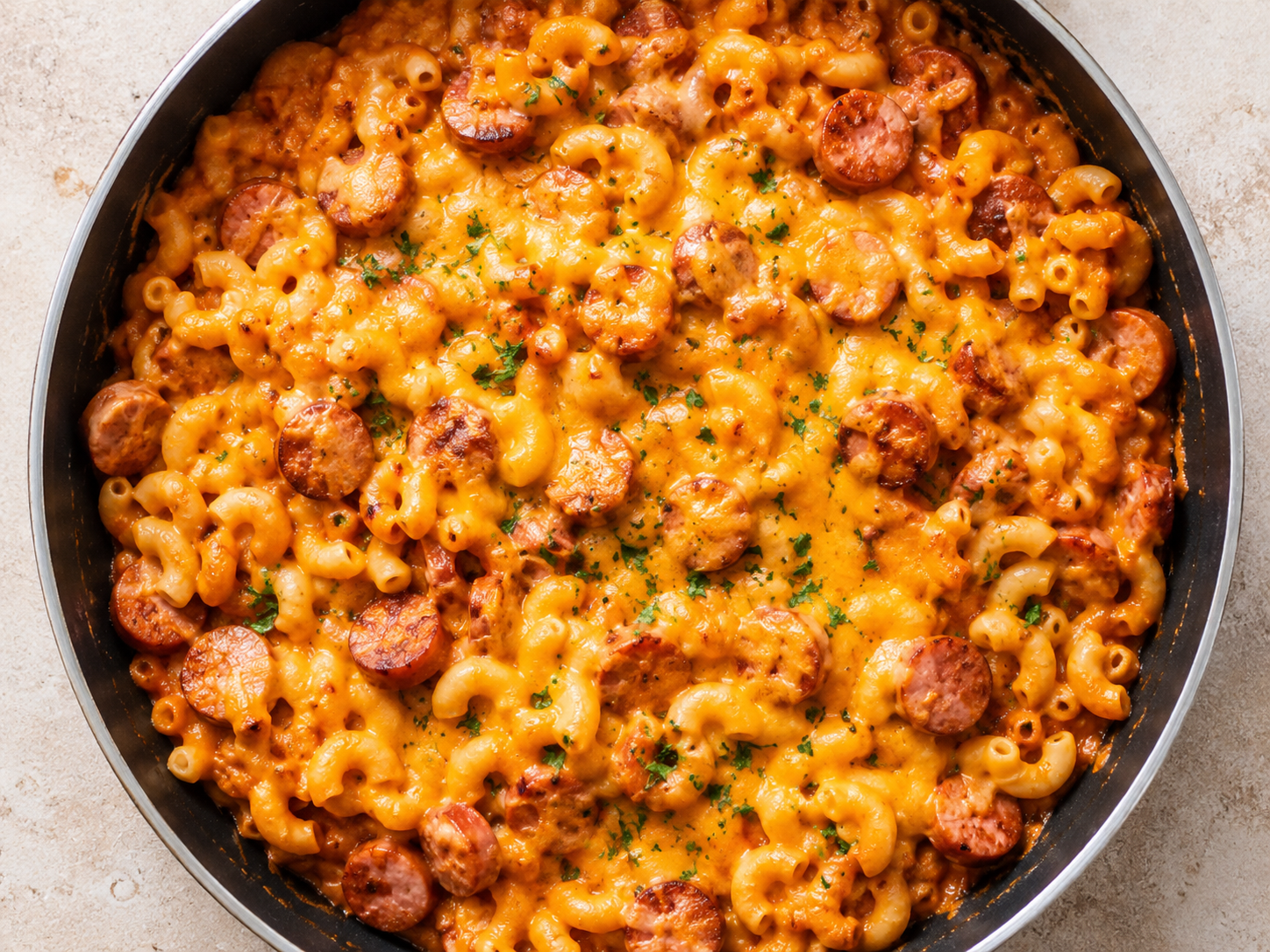 One Pan Cheesy Hot Dog Pasta in a skillet with sliced hot dogs, tender pasta, tomato sauce, and melted cheddar cheese