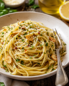 Spaghetti aglio e olio in a bowl with toasted garlic, parsley, red pepper flakes, and grated cheese